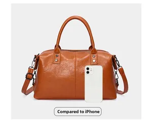 Braune Boston-Tasche Größenvergleich mit iPhone zeigt geräumigen Stauraum und Leder