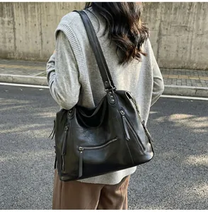 Detail of black PU leather tote bag featuring multiple zippers and silver rivet studs