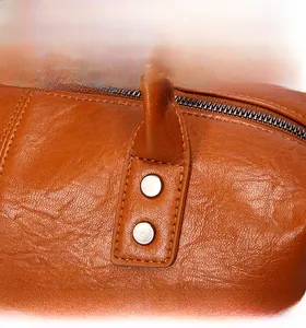 Detail der orangebraunen Lederhandtasche mit Silbernieten und Metallreißverschluss