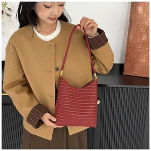 Detail of red hobo bag featuring woven texture and golden metal strap buckles