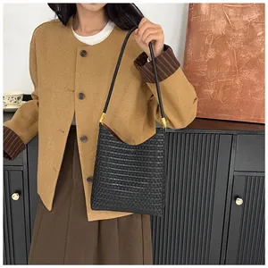 Detail of black woven leather shoulder bag with elegant gold hardware on female model
