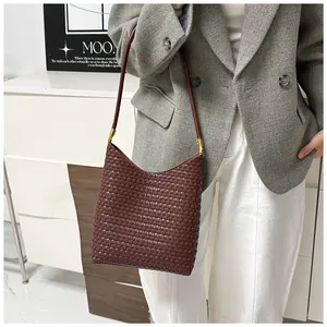 Detail of dark brown woven tote bag featuring fine leather texture and gold hardware