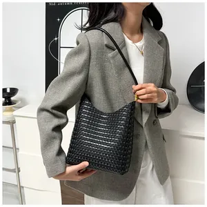 Close-up of black woven leather texture and elegant gold buckle detail on a tote bag