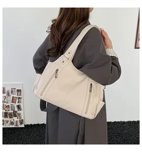 Detail of cream white leather tote bag with vertical zippers shown on shoulder