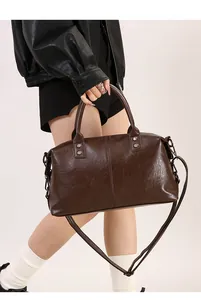 Detail der dunkelbraunen Handtasche mit verstellbarem Riemen und Metallnieten