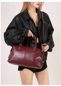 Detail der burgunderroten Boston-Tasche aus Kunstleder mit Doppelgriffen und Metallschnallen