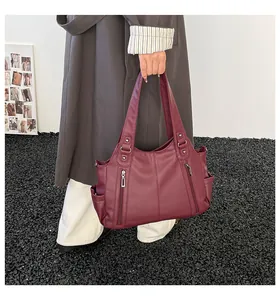 Detail view of burgundy tote bag with pebble leather texture and vertical zipper pockets