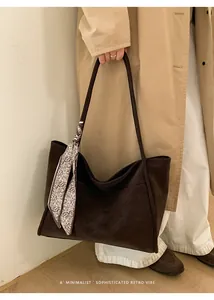 Detail of dark brown matte tote bag with long straps and a paisley pattern silk scarf