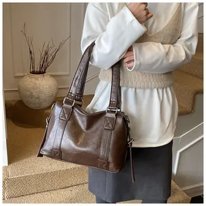 Close-up of vintage brown leather tote bag with reinforced cross-stitching on double handles