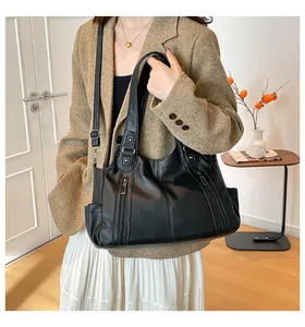 Close-up of black lychee-grain leather tote bag with rivet details and decorative zippers