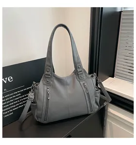 Close-up of grey pebbled leather tote bag with silver zippers and adjustable shoulder strap