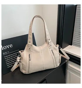 Macro detail of off-white lychee grain leather tote bag with stylish metal zipper pockets