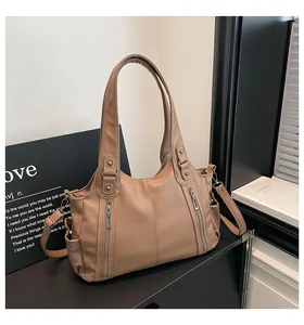 Detail of khaki tote bag featuring lychee texture leather and dual vertical zippers