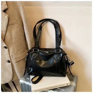 Detail of silver dual zippers and reinforced stitching on a black faux leather bag