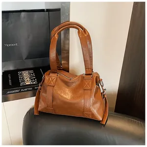 Detailed view of the brown leather bag showing the X-shaped reinforced stitching and zipper