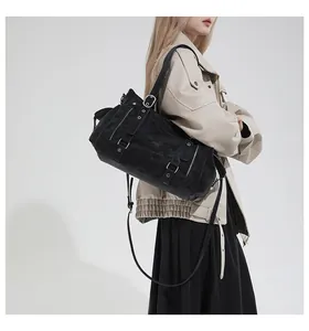 Detail einer schwarzen matten Leder-Tote-Bag mit Nieten und Schnallen am Model