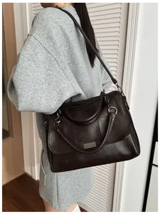 Detailed view of deep brown Boston bag with square stitching and metal decor on a model