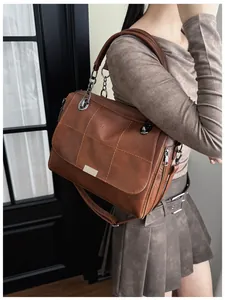 Close-up of retro brown Boston bag with quilted stitching and metal chain strap detail
