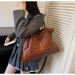 Braune Vintage Handtasche mit Nieten und Fransen Detail am Modell in urbaner Umgebung