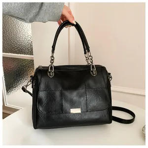 Detail of black plaid patchwork PU leather bag with metal chain and rectangular logo plate