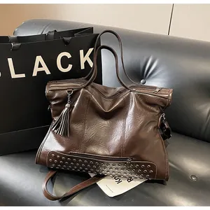 Detailaufnahme der braunen Handtasche mit silbernen Nieten und Fransenanhänger