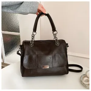Detailed view of the dark brown quilted faux leather texture and metallic accents on bag