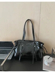 Detailed shot of a black oil wax leather tote bag with stylish vertical zippers and side drawstrings