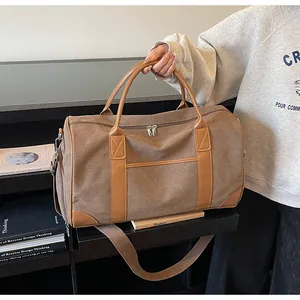 Detail der braunen Canvas-Reisetasche mit Lederakzenten und verstärkten Griffen