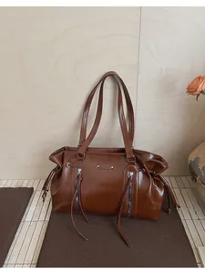 Detailed close-up of brown oiled leather tote bag with vertical zippers and dual straps