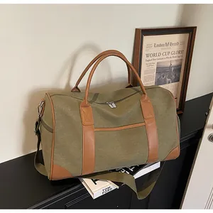 Detail der armeegrünen Canvas-Reisetasche mit braunen Ledergriffen und Metallbeschlägen