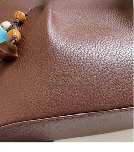 Detail der braunen Shopper aus genarbtem Leder mit bunten Perlen-Anhänger im Retro-Stil