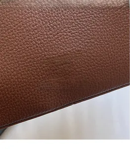 Gros plan sur la texture en cuir marron grainé avec le logo Fashion Bag embossé