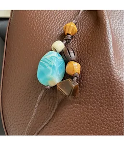 Nahaufnahme des Boho-Perlenanhängers mit Marmor- und Holzperlen an einer Ledertasche