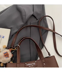 Macro detail of brown lychee grain leather bag with metal plate and plush bear charm