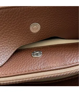 Détail du fermoir magnétique et de la poche zippée à l'intérieur d'un sac cabas en cuir brun