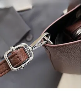 Detailaufnahme der silbernen Metallbeschläge und des Lederriemens mit Lychee-Maserung