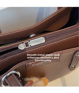 Close-up of smooth silver zipper pull on lychee texture brown leather handbag
