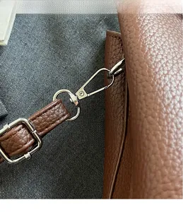 Gros plan du crochet métallique argenté et du cuir marron texturé d'un sac à bandoulière
