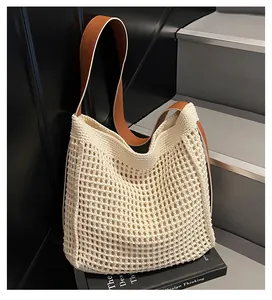 Vue détaillée du sac cabas tissé beige avec bandoulière en cuir marron sur escalier