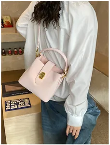 Detailed close-up of soft pink leather bucket bag with elegant golden twist lock hardware