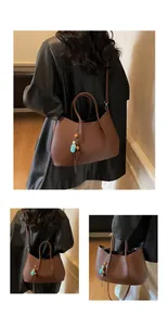 Detaillierte Ansicht einer braunen Tote-Tasche aus Leder mit Perlenanhänger und Schultergurt