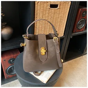 Detailed view of brown bucket bag with gold twist lock and smooth matte leather texture