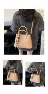 Gros plan sur un sac à main beige en cuir avec pendentif tressé et bandoulière réglable