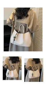 Detail der minimalistischen cremefarbenen Ledertasche mit Vintage-Anhänger und Gurt