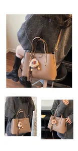 Detail of brown lychee texture tote bag with plush lion charm and tassel accent