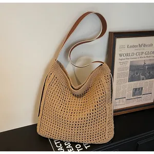 Détail du sac cabas en paille tressée avec bandoulière en cuir marron et texture