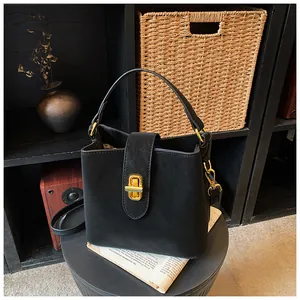 Detail of black bucket bag with golden twist lock and detachable shoulder strap