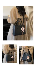 Detail of black lychee grain leather crossbody bag with cute plush bear charm accessory