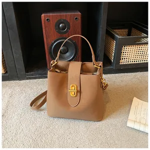 Detail of tan leather bucket bag with gold twist lock and adjustable shoulder strap