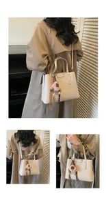 Detail of lychee textured cream crossbody bag with a plush pompom and tassel charm